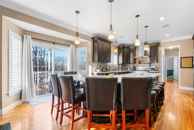 10 Von Trapp Ct, Washingtonville, NY 10992 - kitchen with wall chimney exhaust hood, crown molding, dark brown cabinetry, light countertops, and light wood-style floors