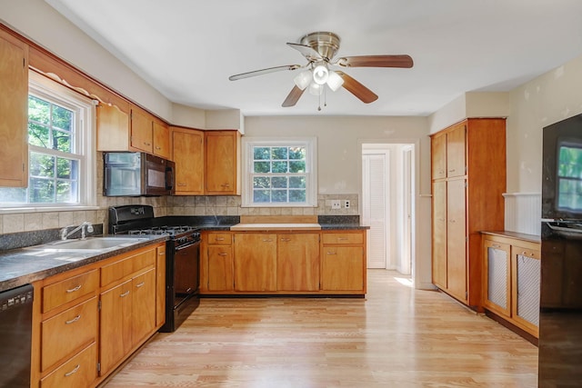 126 Carman St, Patchogue, NY 11772 - kitchen with black appliances, light wood-style floors, tasteful backsplash, dark countertops, and brown cabinetry