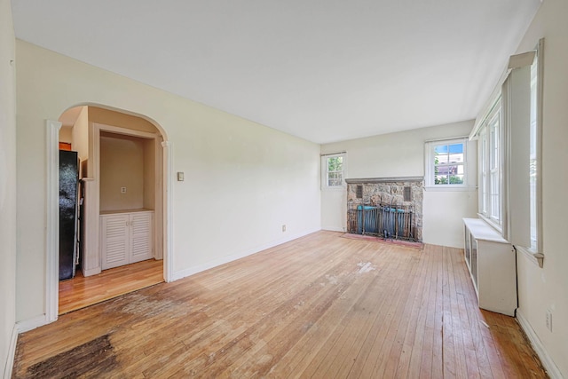 126 Carman St, Patchogue, NY 11772 - unfurnished living room featuring a fireplace, light wood-type flooring, and arched walkways