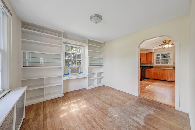 126 Carman St, Patchogue, NY 11772 - empty room featuring light wood-style floors, radiator, arched walkways, built in features, and ceiling fan
