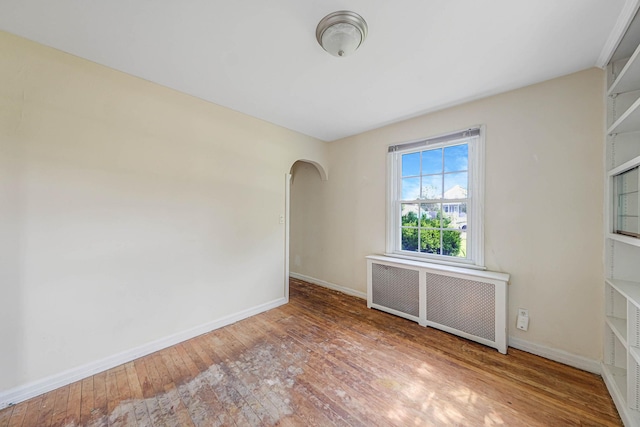 126 Carman St, Patchogue, NY 11772 - spare room with radiator, arched walkways, and hardwood / wood-style floors
