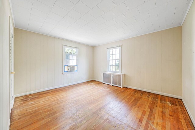 126 Carman St, Patchogue, NY 11772 - empty room with wood-type flooring, radiator, wood walls, and cooling unit