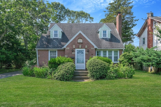 126 Carman St, Patchogue, NY 11772 - view of front of home featuring brick siding, a front yard, a chimney, and a shingled roof