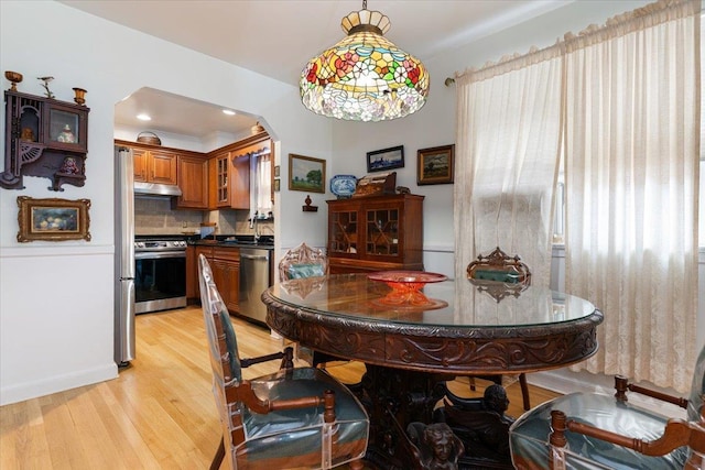 1528 Rhinelander Ave, Bronx, NY 10461 - dining room featuring light wood-style floors, arched walkways, and healthy amount of natural light