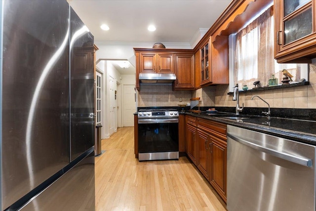 1528 Rhinelander Ave, Bronx, NY 10461 - kitchen with appliances with stainless steel finishes, brown cabinetry, under cabinet range hood, dark stone countertops, and light wood-style flooring