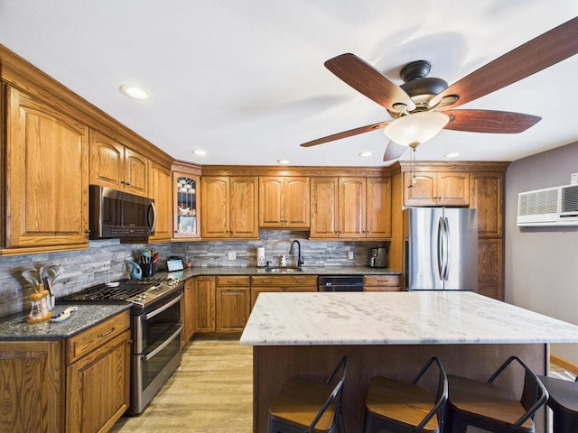 12 Turin St, East Patchogue, NY 11772 - kitchen with appliances with stainless steel finishes, brown cabinets, a kitchen bar, light stone counters, and a ceiling fan