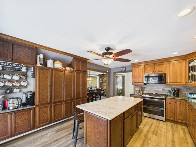 12 Turin St, East Patchogue, NY 11772 - kitchen with appliances with stainless steel finishes, light wood-style flooring, a ceiling fan, tasteful backsplash, and a kitchen island