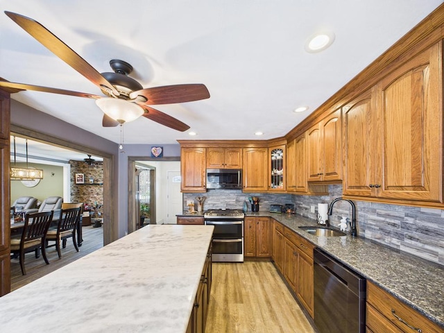 12 Turin St, East Patchogue, NY 11772 - kitchen featuring appliances with stainless steel finishes, brown cabinets, decorative backsplash, dark stone counters, and ceiling fan