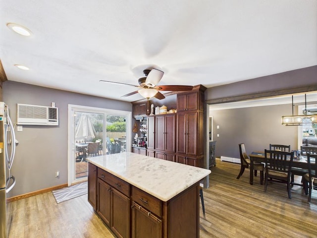 12 Turin St, East Patchogue, NY 11772 - kitchen featuring a wall unit AC, a ceiling fan, light wood-style flooring, light countertops, and a center island