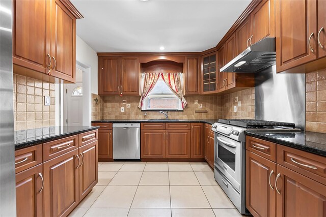 50-55 Cloverdale Blvd, Bayside, NY 11364 - kitchen with stainless steel appliances, under cabinet range hood, dark stone counters, brown cabinets, and light tile patterned flooring