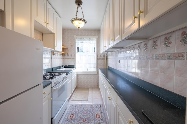 251 Seaman Ave Unit 6A, New York Manhattan, NY 10034 - kitchen featuring white appliances, dark countertops, light tile patterned flooring, wallpapered walls, and white cabinetry
