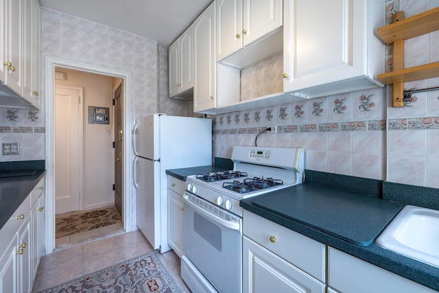 251 Seaman Ave Unit 6A, New York Manhattan, NY 10034 - kitchen featuring white appliances, dark countertops, decorative backsplash, white cabinetry, and light tile patterned floors