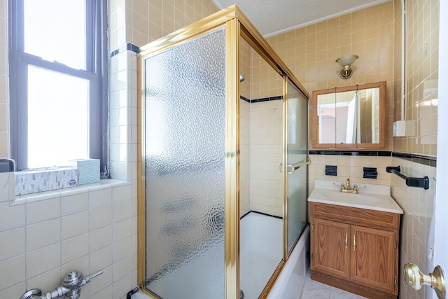 251 Seaman Ave Unit 6A, New York Manhattan, NY 10034 - full bathroom featuring tile walls, plenty of natural light, bath / shower combo with glass door, and vanity