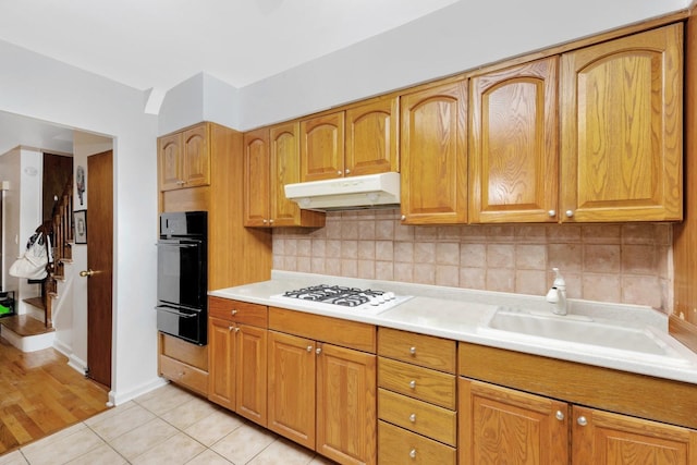 66-48 73rd Pl, Middle Village, NY 11379 - kitchen with black oven, under cabinet range hood, white gas cooktop, a warming drawer, and light countertops
