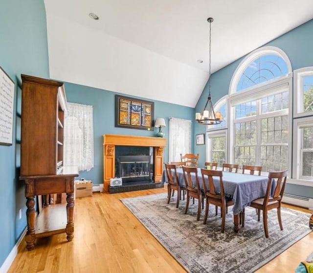48 Brennan Ct, Chester, NY 10918 - dining space featuring wood finished floors, a chandelier, a glass covered fireplace, and high vaulted ceiling