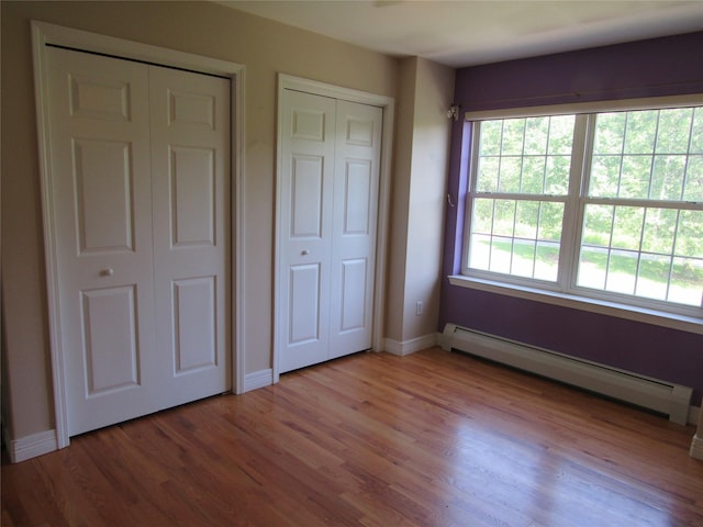 48 Brennan Ct, Chester, NY 10918 - unfurnished bedroom with a baseboard heating unit, two closets, and light wood finished floors