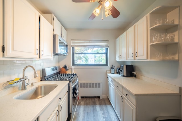 218-12 73rd Ave Unit 401A1, Oakland Gardens, NY 11364 - kitchen featuring stainless steel appliances, radiator heating unit, ceiling fan, white cabinetry, and light wood-style flooring