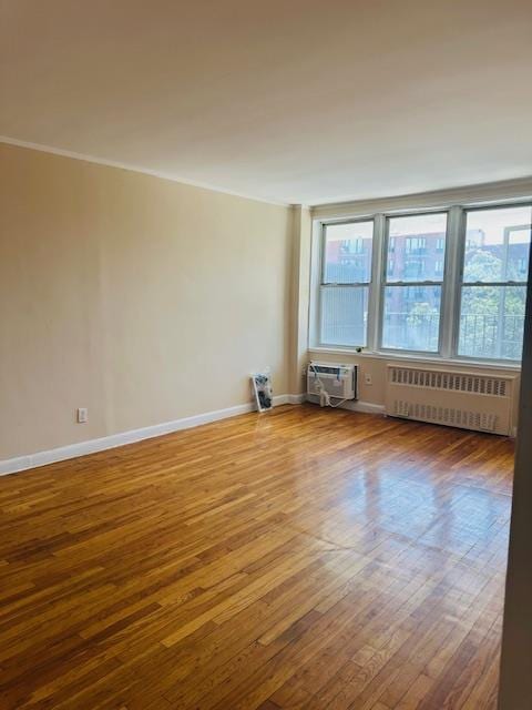 86-05 60th Rd Unit 2E, Elmhurst, NY 11373 - empty room with radiator heating unit, wood finished floors, and a wall mounted AC