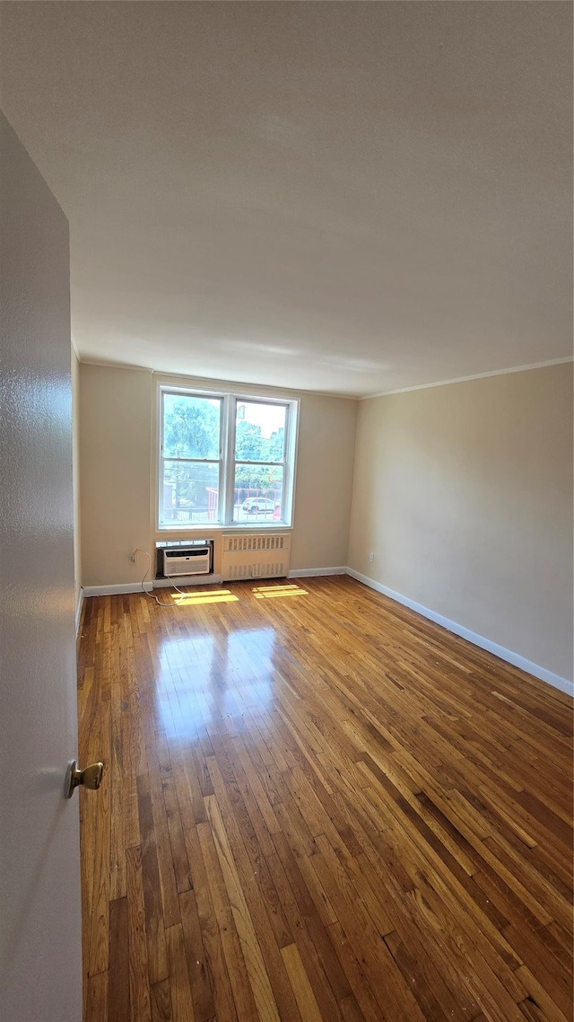 86-05 60th Rd Unit 2E, Elmhurst, NY 11373 - unfurnished room featuring a wall mounted air conditioner, wood-type flooring, and radiator heating unit