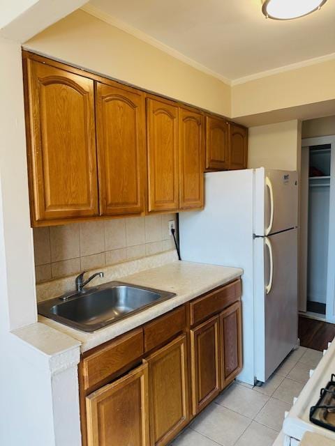 86-05 60th Rd Unit 2E, Elmhurst, NY 11373 - kitchen featuring light countertops, brown cabinets, light tile patterned floors, tasteful backsplash, and ornamental molding