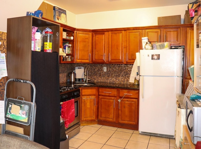 1460 Commonwealth Ave, Bronx, NY 10460 - kitchen featuring freestanding refrigerator, stainless steel gas stove, light tile patterned floors, backsplash, and brown cabinetry