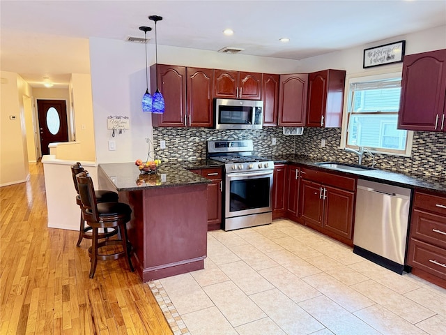 467 Scranton Ave, Lynbrook, NY 11563 - kitchen featuring appliances with stainless steel finishes, dark brown cabinets, a kitchen bar, hanging light fixtures, and decorative backsplash