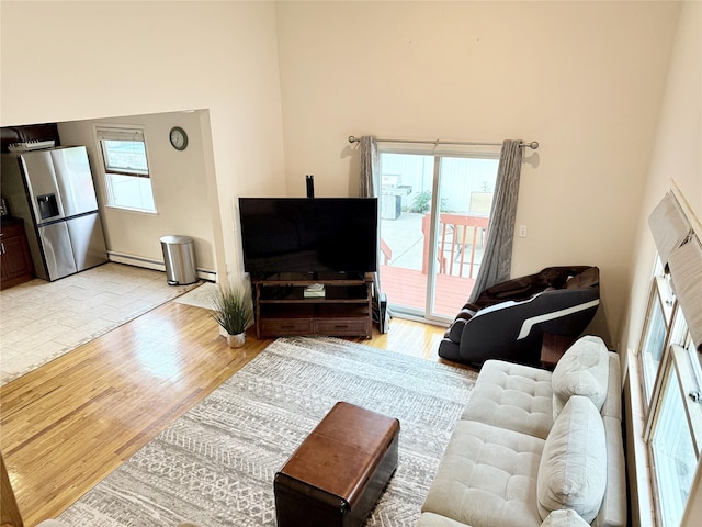 467 Scranton Ave, Lynbrook, NY 11563 - living area featuring a high ceiling, baseboard heating, light wood-type flooring, and plenty of natural light