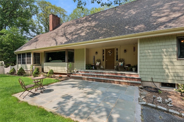 23 Bacon Rd, Head Of The Harbor, NY 11780 - view of exterior entry featuring a shingled roof, a chimney, a yard, and a porch