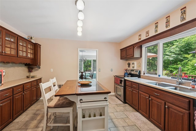 23 Bacon Rd, Head Of The Harbor, NY 11780 - kitchen featuring stainless steel range with electric cooktop, light countertops, a kitchen bar, and glass insert cabinets