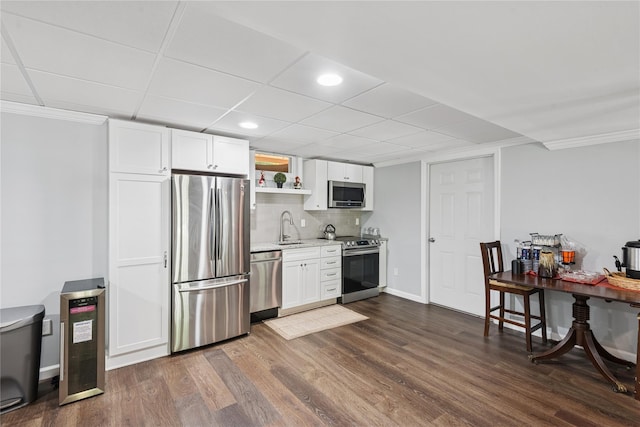 23 Bacon Rd, Head Of The Harbor, NY 11780 - kitchen with stainless steel appliances, white cabinetry, dark wood finished floors, crown molding, and tasteful backsplash