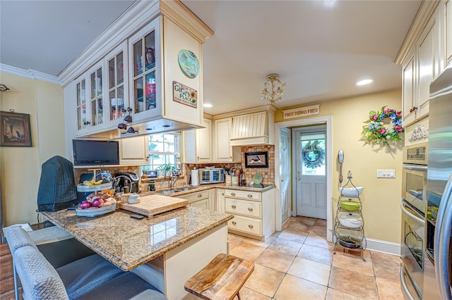227 Elm St, West Hempstead, NY 11552 - kitchen with cream cabinetry, plenty of natural light, a peninsula, glass insert cabinets, and recessed lighting