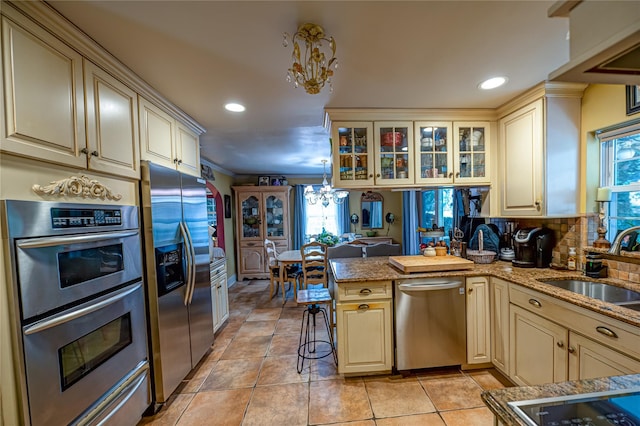227 Elm St, West Hempstead, NY 11552 - kitchen featuring stainless steel appliances, cream cabinetry, a chandelier, plenty of natural light, and recessed lighting