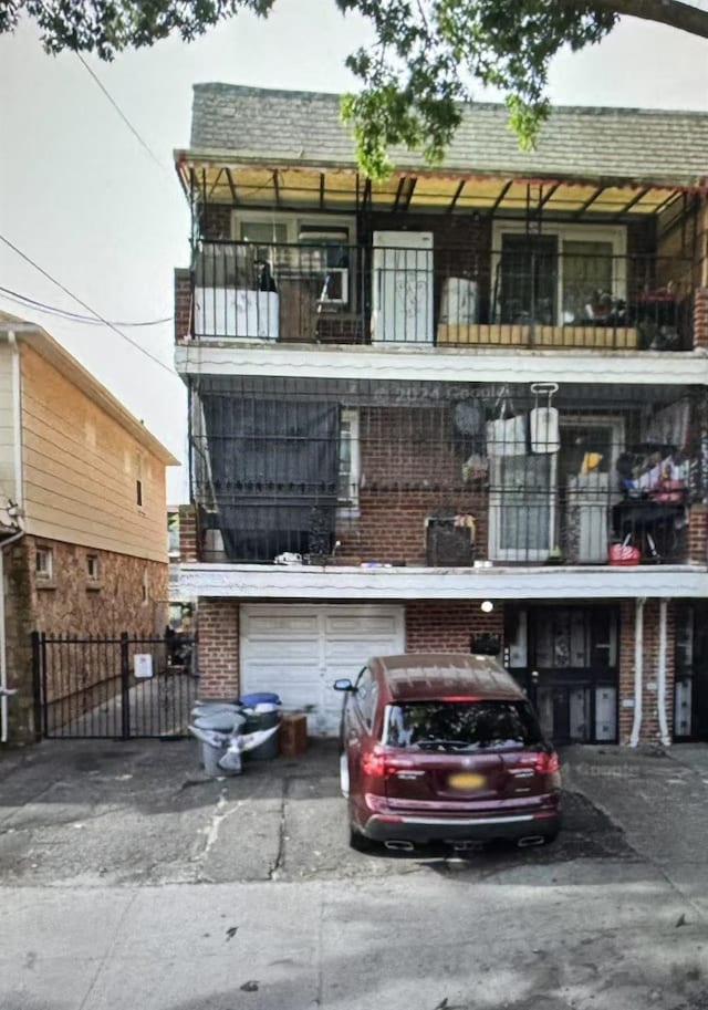 57-54 Van Doren St, Corona, NY 11368 - view of front of house featuring a balcony, an attached garage, asphalt driveway, and brick siding