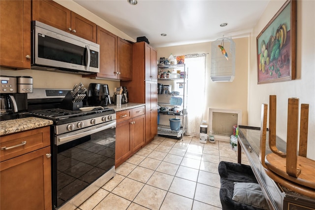 93 Edgewood Ave, Yonkers, NY 10704 - kitchen with stainless steel appliances, brown cabinetry, light tile patterned floors, light stone countertops, and recessed lighting
