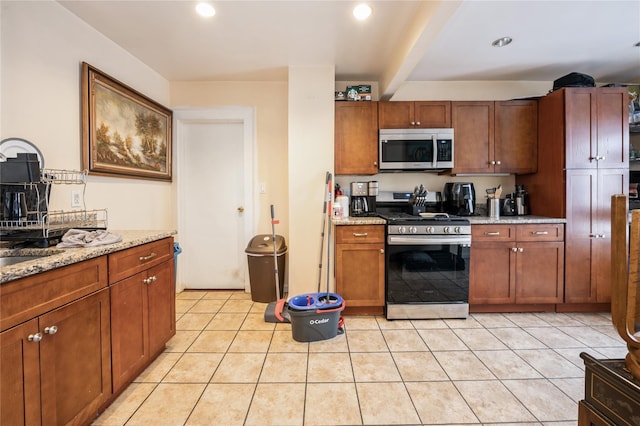 93 Edgewood Ave, Yonkers, NY 10704 - kitchen with stainless steel appliances, light stone counters, light tile patterned flooring, recessed lighting, and brown cabinetry