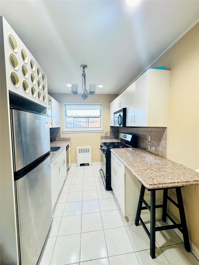 82-09 268th St Apt B, New Hyde Park, NY 11040 - kitchen featuring stainless steel appliances, radiator heating unit, a chandelier, tasteful backsplash, and white cabinetry
