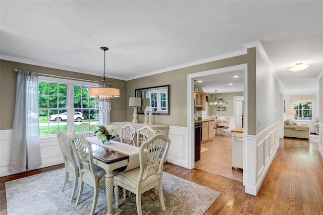 1 Willis Ave, Port Jefferson, NY 11777 - dining room with a chandelier, a decorative wall, light wood-style flooring, a wainscoted wall, and ornamental molding