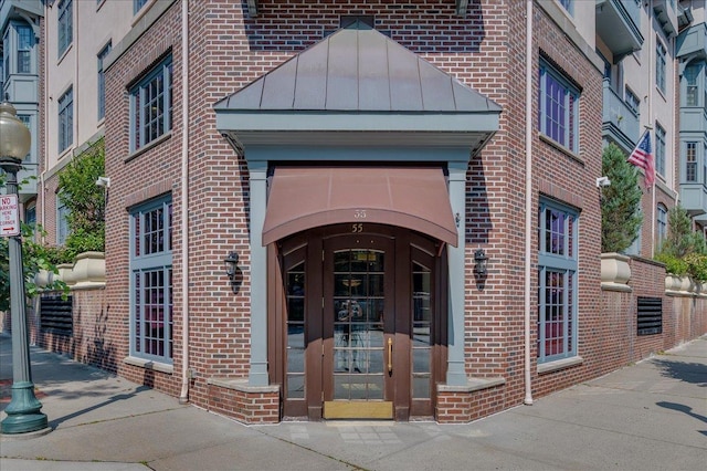 55 1st St Unit 207, Pelham, NY 10803 - doorway to property featuring brick siding, a standing seam roof, and a metal roof