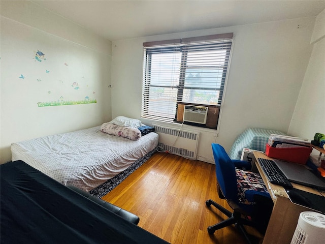 63-84 Saunders St Unit 2G, Rego Park, NY 11374 - bedroom with radiator heating unit, cooling unit, and wood finished floors