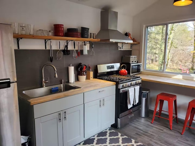 39 E James Ave, Smallwood, NY 12778 - kitchen featuring appliances with stainless steel finishes, wall chimney range hood, open shelves, decorative backsplash, and light wood-type flooring