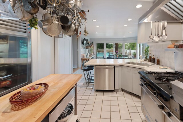 56 Tuthill Point Rd, East Moriches, NY 11940 - kitchen featuring dishwasher, light tile patterned floors, a peninsula, recessed lighting, and decorative backsplash