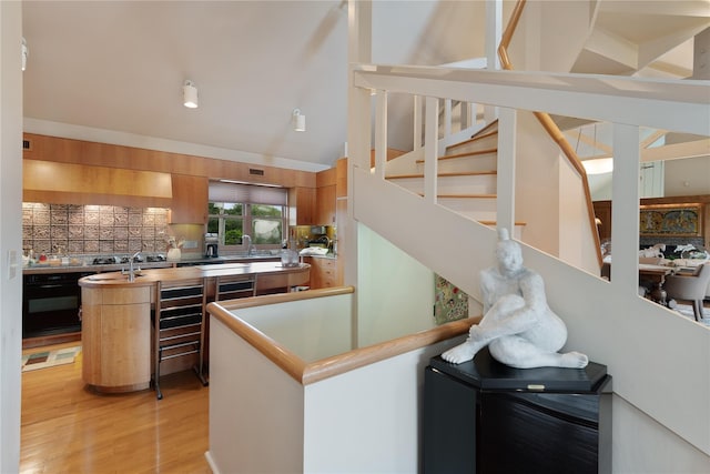 56 Tuthill Point Rd, East Moriches, NY 11940 - kitchen with oven, light wood-style floors, decorative backsplash, vaulted ceiling, and an island with sink