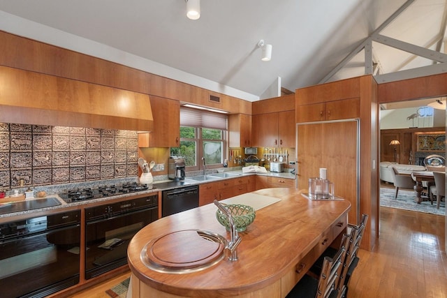 56 Tuthill Point Rd, East Moriches, NY 11940 - kitchen with black appliances, brown cabinets, vaulted ceiling, backsplash, and light wood finished floors