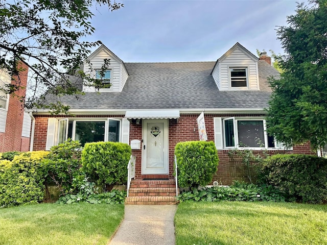 26612 82nd Ave, Floral Park, NY 11004 - cape cod house with brick siding, roof with shingles, a front yard, entry steps, and a chimney
