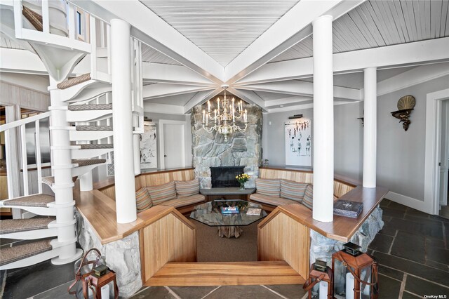 174 Dune Rd, Quogue, NY 11959 - living area with stone tile floors, beamed ceiling, a chandelier, and a stone fireplace