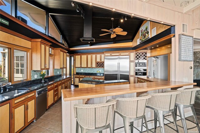 174 Dune Rd, Quogue, NY 11959 - kitchen featuring built in appliances, lofted ceiling, decorative backsplash, tile patterned flooring, and dark countertops