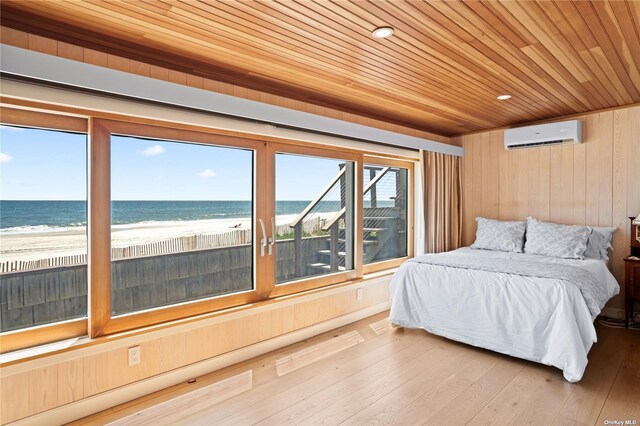 174 Dune Rd, Quogue, NY 11959 - bedroom featuring a wall unit AC, wood ceiling, wood walls, view of water and beach, and wood finished floors