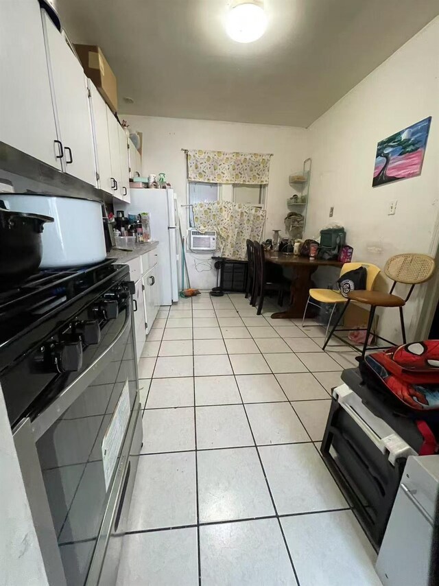 103-23 51st Ave, Corona, NY 11368 - kitchen featuring black gas range, white cabinets, light tile patterned floors, freestanding refrigerator, and light countertops