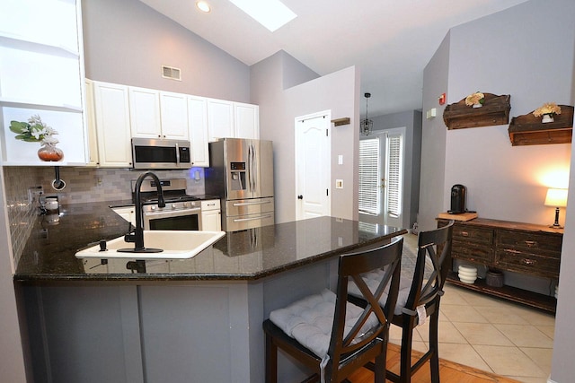 1405 Constance Ln, Port Jefferson Station, NY 11776 - kitchen featuring appliances with stainless steel finishes, a peninsula, backsplash, white cabinets, and dark stone countertops
