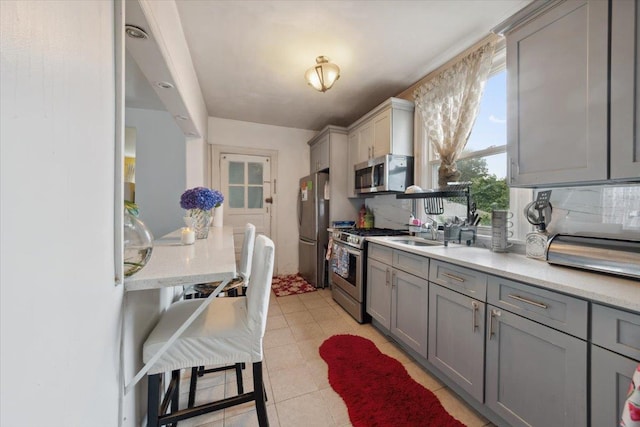317 Hawthorne Ave, Yonkers, NY 10705 - kitchen with appliances with stainless steel finishes, gray cabinetry, light stone countertops, decorative backsplash, and light tile patterned flooring
